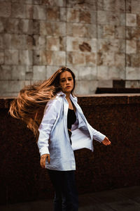 Young woman standing against wall