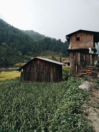 House on field by mountain against sky