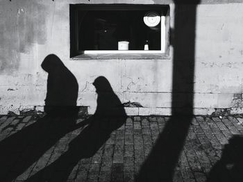 Shadow of man and woman sitting on wall
