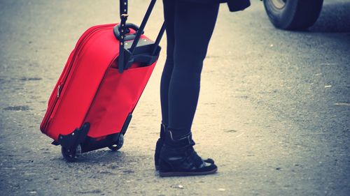 Low section of man with luggage standing on street