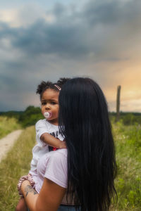 Mother and daughter on field against sky