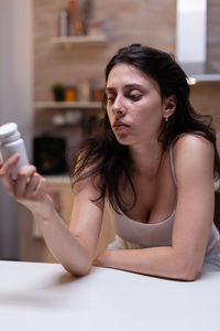 Young woman using mobile phone while sitting on table