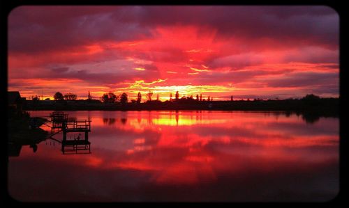 Scenic view of lake against cloudy sky at sunset