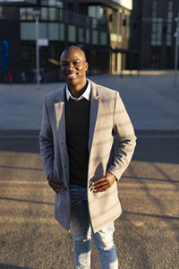 Smiling businessman in long coat standing on road