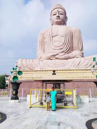 Statue of man standing by building against sky