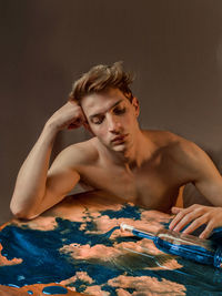 Portrait of young man sitting against black background