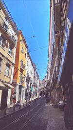 Street amidst buildings against blue sky