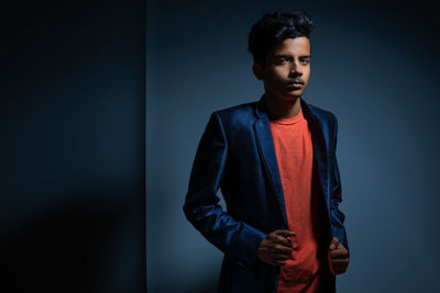 Portrait of boy in blazer standing against wall