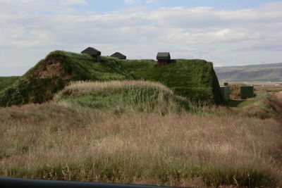Scenic view of grassy field against cloudy sky