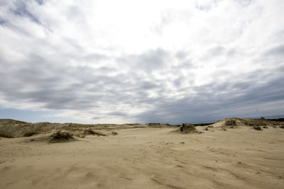 Scenic view of sand dunes against sky