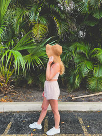 Full length of woman standing against palm trees