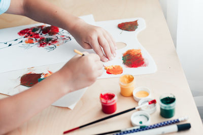 Close uo of child sitting at desk and making picture from dry birch leaves. autumn activities