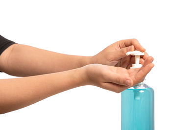Close-up of hand holding bottle against white background