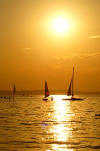 Silhouette sailboat sailing on sea against sky during sunset