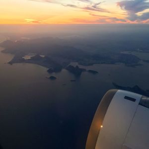 Aerial view of airplane wing over sea against sky