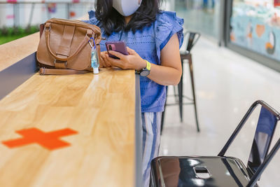 Midsection of woman holding umbrella while standing on table