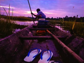 Man on boat against sky during sunset