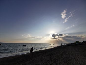 Silhouette people on beach against sky during sunset