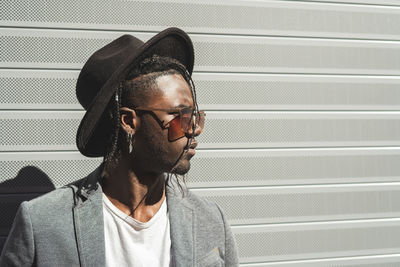 Portrait of young man looking away against wall