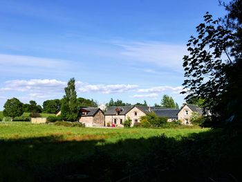 Trees and farmer's house on field against sky