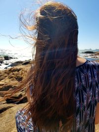 Rear view of woman at beach against sky