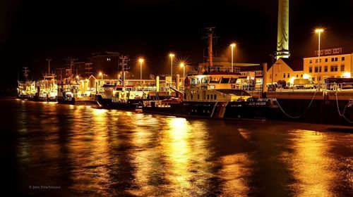 Boats moored at harbor against sky at night