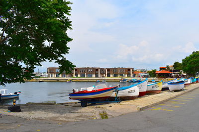 Boats moored at harbor against sky