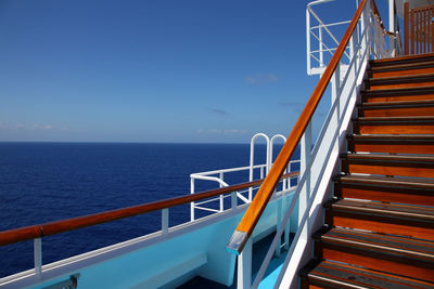 Staircase by sea against blue sky