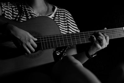 Midsection of woman playing guitar