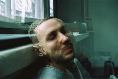 Portrait of man sitting on window