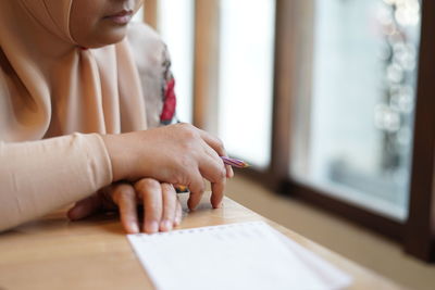 Midsection of woman writing in book