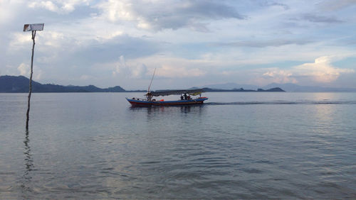 Boats in sea against cloudy sky