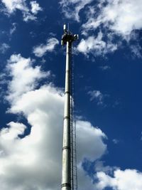 Low angle view of communications tower and building against sky