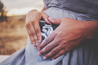 Midsection of pregnant woman holding x ray