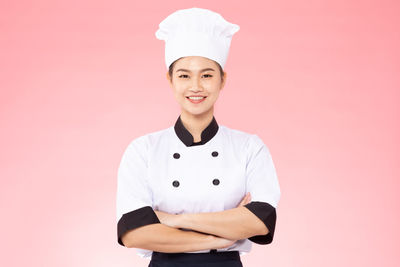 Portrait of smiling young chef against pink background