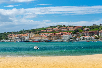 Scenic view of sea by townscape against sky