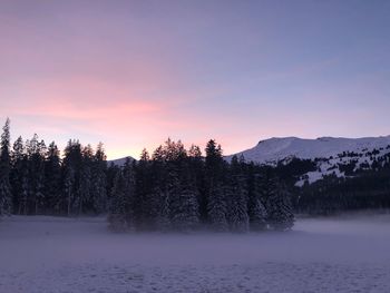 Scenic view of snow covered land against sky at sunset