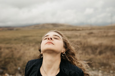 Portrait of beautiful young woman against sky