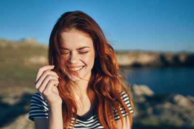 Portrait of smiling young woman against sky