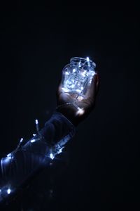 Close-up of hand holding glass against black background