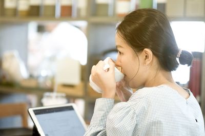 Close-up of woman drinking coffee sitting at cafe