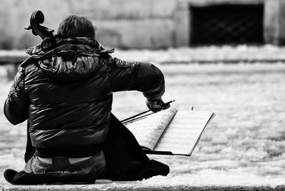 Rear view of musician playing double bass at street during winter