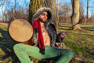 Portrait of senior man sitting on tree trunk