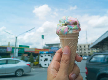 Hand holding ice cream cone on street