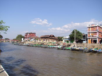 Boats in canal by city against sky