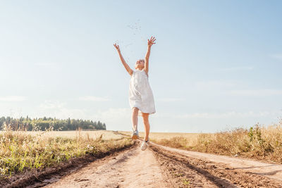 Full length of girl jumping on land against sky