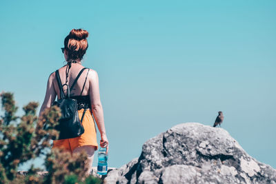 Rear view of woman standing on rock
