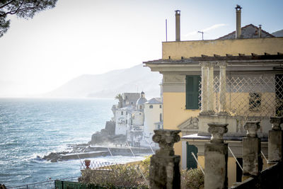 Buildings by sea against clear sky