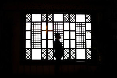 Silhoutte of a man standing beside the window