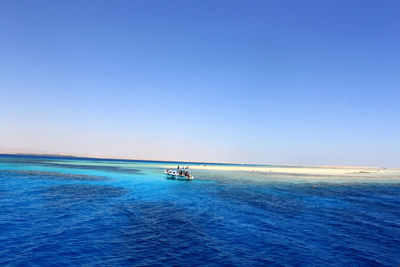 Boat on sea against clear blue sky